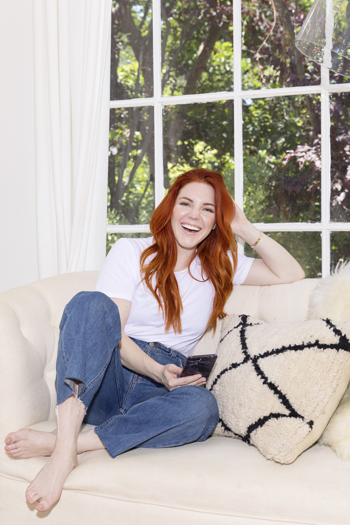 Girl with red hair sitting on a white sofa. Kim Genevieve Los Angeles Portrait Photographer