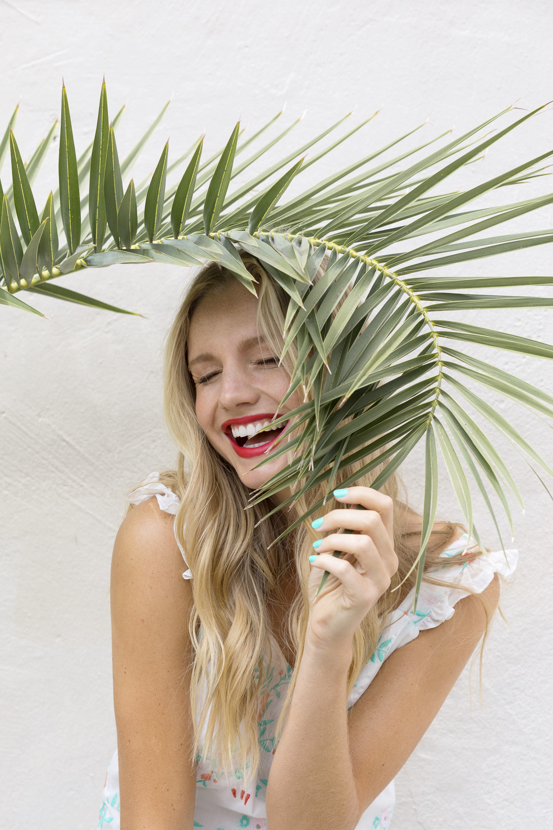 Millennial laughing and hiding behind a palm leaf - Kim Genevieve Los Angeles Lifestyle Photographer