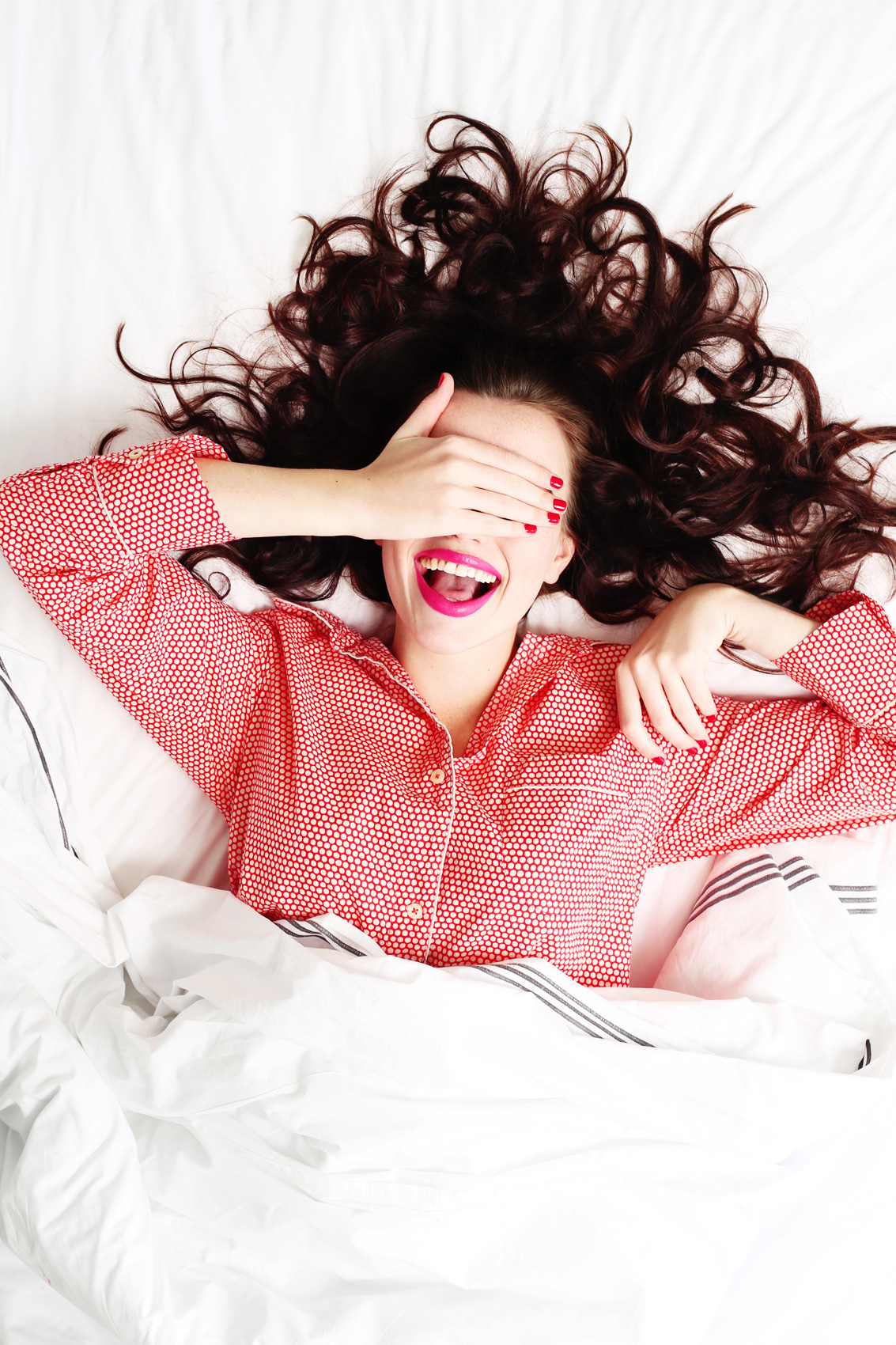 Smiling girl in bed with red polka-dot pyjamas - Kim Genevieve Los Angeles Lifestyle Photographer