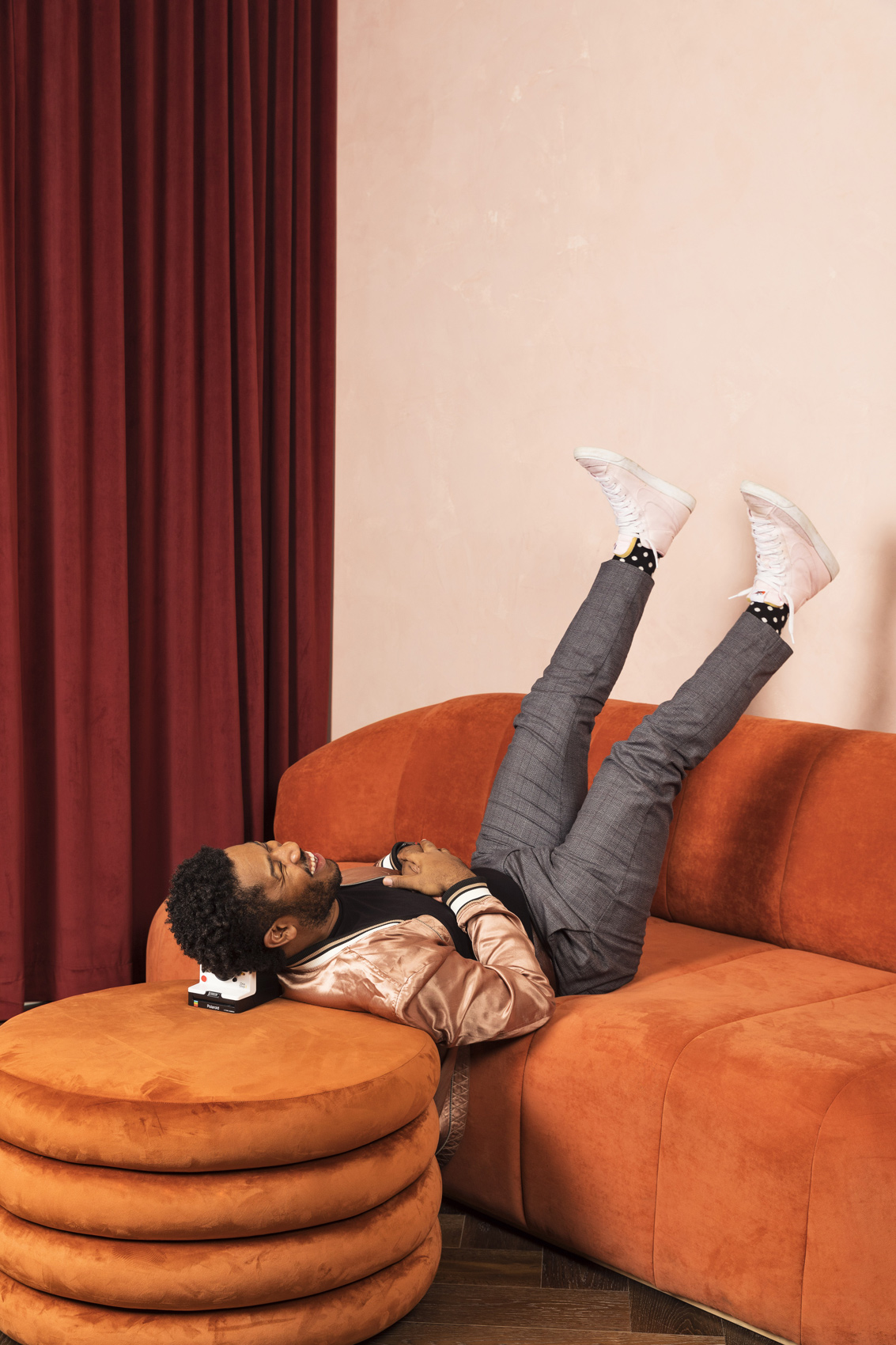 Laughing man sitting upside down on an orange sofa - Kim Genevieve Los Angeles Lifestyle Photographer
