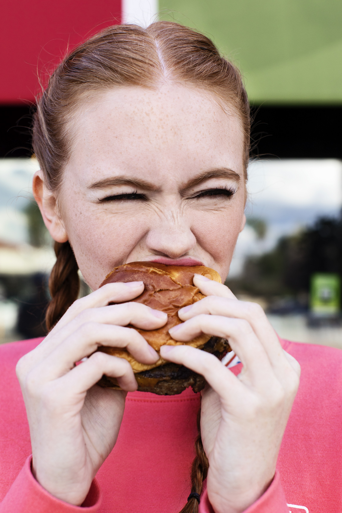 Girl with red hair eating a hamburger outside. Kim Genevieve Los Angeles Lifestyle Photographer